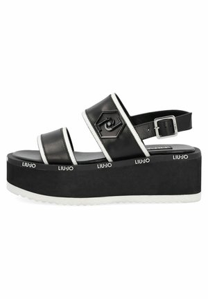 Sandale à plateforme noire avec un bord blanc, bride de cheville réglable, détail de logo hexagonal et marquage "LIU·JO" sur le bord de la semelle.