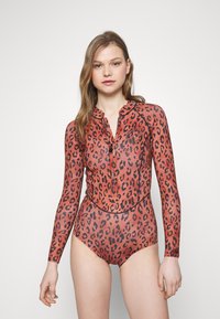 Långärmad baddräkt i orange-röd med svart leopardmönster. Har dragkedja och kragdesign. Slät textur hela vägen.