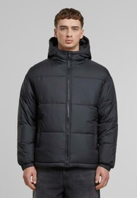 Sort puffjakke med hætte, med et kviltet design, frontlynlås og elastiske manchetter, lavet af et glat, let materiale.