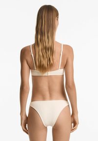 Set de bikini bej cu o textură ribbed. Bretele ajustabile și un închidere simplă la spate. Design minimalist cu slipuri de tăiere clasică.