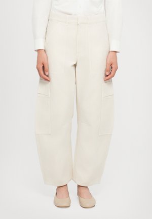 Cotton cargo pants in off-white with a wide-leg design. Features large side pockets and a smooth texture. Paired with beige shoes.