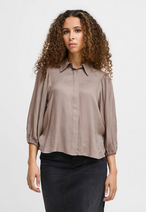 Light brown, long-sleeve blouse in smooth fabric; features a classic collar and gathered sleeves, creating a loose-fit silhouette.