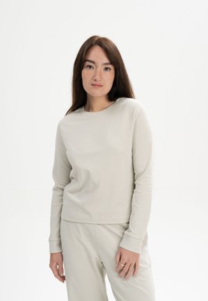 Hellgraues Langarmshirt aus weichem Stoff, mit Rundhalsausschnitt und geradem Saum, kombiniert mit passenden hellgrauen Hosen.