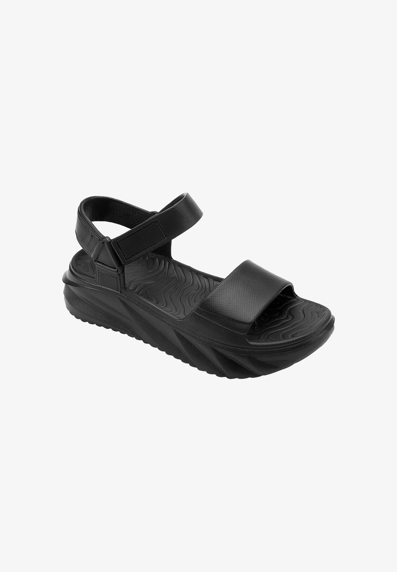 Sandale sportive noire avec bride de cheville ajustable, large bride à l’avant et semelle texturée avec motif ondulé pour une meilleure adhérence et confort.