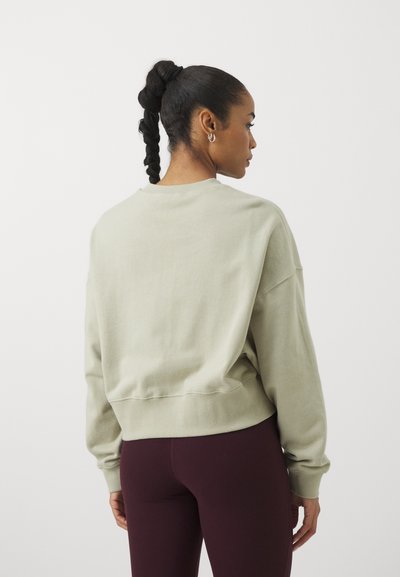Light green cropped sweatshirt with a round neckline and long sleeves; soft texture; simple design; paired with dark maroon legging.