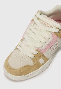 Bézs és rózsaszín sneaker, velúr és hálós kialakítással, párnázott bokarésszel, perforált orral és krémszínű fűzővel. Logó részlet az oldalon.