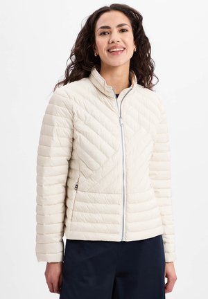 Hellbeige isolierte Jacke mit einer gesteppten Textur, hohem Kragen und durchgehendem Reißverschluss. Sie verfügt über diagonale und horizontale Nähmuster.