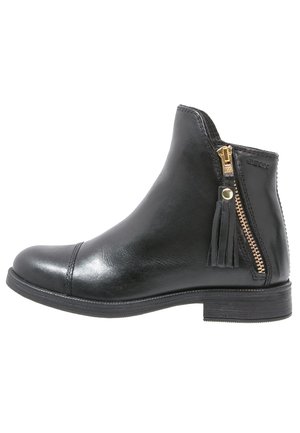 Botte de cheville en cuir noir avec un bout rond, fermeture éclair sur le côté avec quincaillerie dorée, et un accent en frange sur la fermeture. Semelle plate.