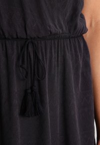 Vestido azul marino con un patrón de diamantes texturizado, cintura elástica y cordón ajustable con borlas. Tela suave, corte relajado.