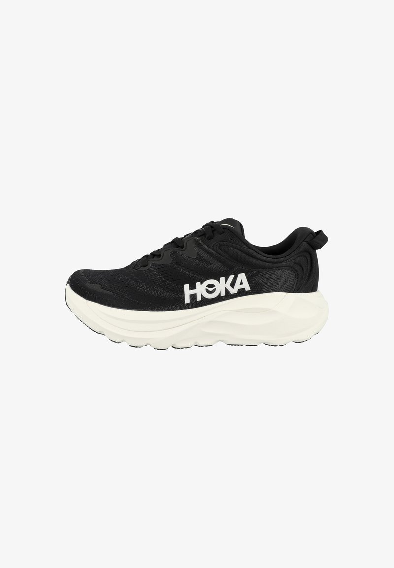 Zwarte Hoka hardloopschoen met dikke witte zool, vetersluiting en groot wit HOKA-logo aan de zijkant.