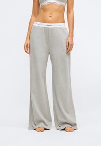 Lys grå, vide joggebukser laget av mykt stoff. Har en elastisk linning med en merket kant og en avslappet passform for komfort.