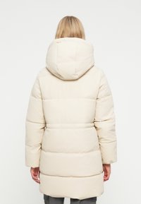 Puffjakke i lys beige med hætte, vandret quiltede sektioner, lange ærmer og en lige silhuet.