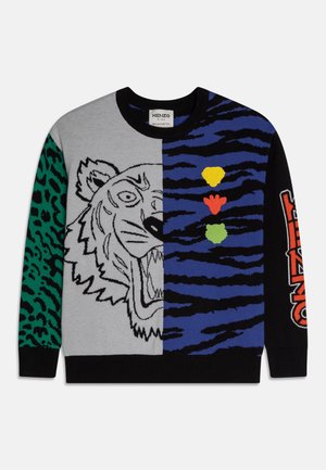 Jersey con diseño de cara de tigre dividida, manga con estampado verde de leopardo, rayas azules y negras, huellas de patas coloridas y texto "KENZO" en la manga negra.