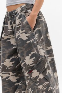 Pantalons cargo camouflage gris et beige, avec une taille élastique, des poches latérales et un détail de couture avec un logo sur la poche.
