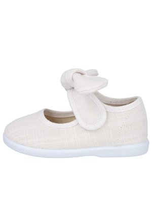 Zapato blanco para niño pequeño tipo Mary Jane con parte superior de tela texturizada, tira ajustable y lazo de tela en la parte superior, mostrado de lado.