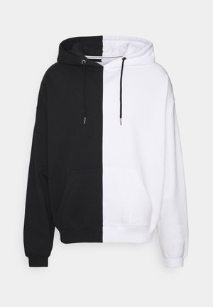 Sudadera con capucha que presenta un diseño dividido: mitad de algodón negro y mitad de algodón blanco. Bolsillo canguro en la parte frontal y cordón ajustable.