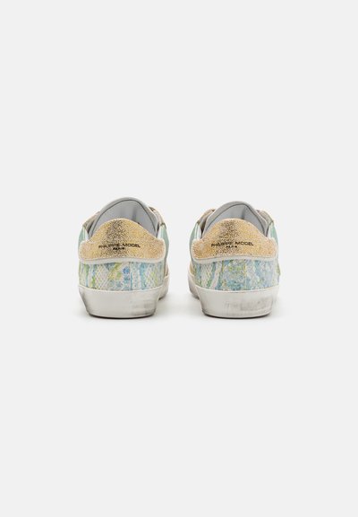 Sneakers z jasnoniebieską i zieloną fakturowaną cholewką, złotymi akcentami na pięcie oraz zużytą białą gumową podeszwą.