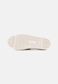 Rubberen schoenzool in beige met een gestructureerd oppervlak en een verticaal gestreept patroon; voorzien van merkopdruk en milde gripgroeven.