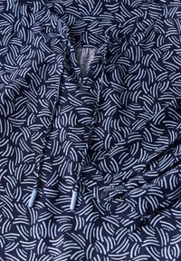 Camicia blu navy con un motivo a linee curve bianche, design a V con coulisse e chiusura a bottone sul manico.