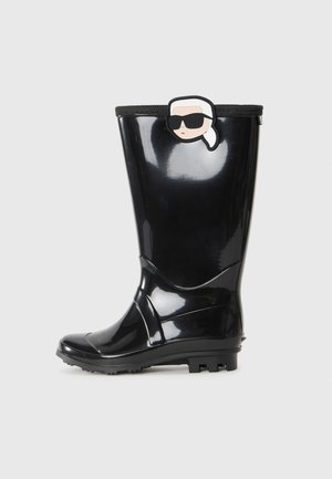 Black glossy rain boot with a cartoon face wearing sunglasses and a white ponytail attached near the top edge.