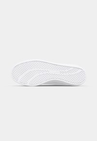Vit sneakersula med en texturerad yta som har cirkulära mönster och synliga spår, utformad för grepp och flexibilitet.