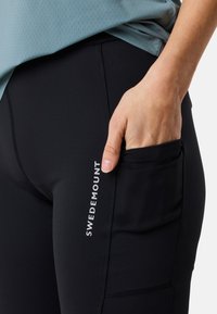 Svarta träningsleggings med sidofickor, med en upphöjd söm och texten "SWEDEMOUNT" i vitt. Mjukt, stretchigt tyg.
