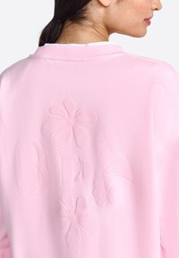 Felpa rosa con design floreali in rilievo e la parola "BELLA". Realizzata in tessuto morbido con un fit rilassato e colletto a girocollo.