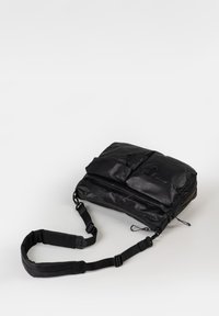 Borsa a spalla nera con design imbottito, dotata di due tasche frontali, tracolla regolabile e materiale liscio e testurizzato.