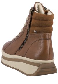 Botte cheville en cuir marron avec un dessus texturé, un col rembourré et une fermeture éclair sur le côté. Caractérisée par une semelle en caoutchouc épaisse de couleur claire pour plus de hauteur.