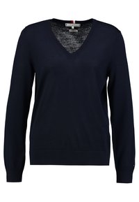 Pull col en V bleu marine en matière tricotée douce. Comprend des manches longues, des poignets côtelés et un ourlet côtelé. Logo de la marque discret sur le côté.