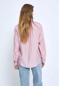 Camicia a maniche lunghe rosa chiaro con strisce bianche verticali, dettagli con bottoni sui polsini e orlo arrotondato. Tessuto morbido con una vestibilità casual.