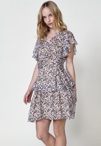 Kleid mit kurzen Ärmeln und Leopardenmuster, verfügt über ein gestuftes Rüschendesign, einen V-Ausschnitt und eine taillierte Taille. Aus leichtem, durchscheinendem Stoff gefertigt.
