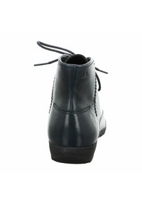 Botines de cuero azul oscuro, con puntera redonda, detalles cosidos y suela de goma plana. Cuenta con cordones en la parte trasera para ajuste.