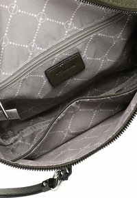Olive green bag interior featuring grey lining with a geometric pattern, zippered pocket, and a small black leather tag.