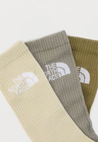Τρία ζευγάρια ριμπ κάλτσες σε μπεζ, γκρι και ελαιδί, το καθένα με λευκό λογότυπο «The North Face» στη μανσέτα.