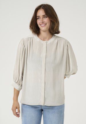Pale grey blouse with vertical stripes, round neckline, and button closure. Features puffed sleeves with gathered cuffs. Worn with light blue jeans.