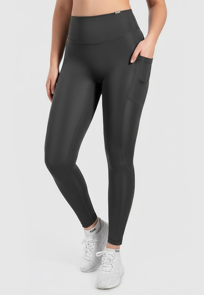 High-waisted black leggings with a smooth, stretchy texture and side pocket. Paired with white athletic shoes.