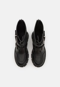 Bottes chevilles en cuir noir avec un bout arrondi, une fermeture éclair latérale et des accents de sangle. Semelle épaisse avec une bande de roulement texturée pour une meilleure adhérence.
