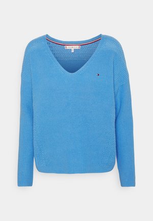 Maglione blu lavorato a maglia con scollo a V, maniche lunghe e motivo testurizzato. Presenta un piccolo logo sul petto e un dettaglio in contrasto all'interno dello scollo.