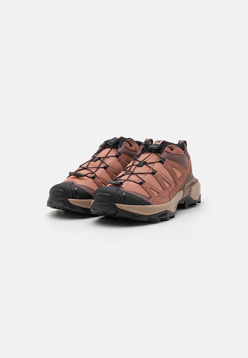 Buty outdoorowe z różowobrunatnym tekstylnym wierzchem, czarnymi akcentami, wzmocnionym przodem oraz teksturowaną gumową podeszwą zapewniającą przyczepność.