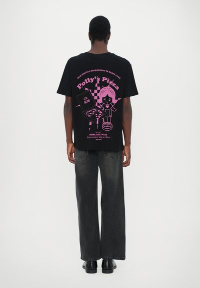 Svart oversized t-skjorte med rosa grafisk design som viser en tegneseriefigur og en pizzaboks. Kombinert med mørkegrå vide bukser.