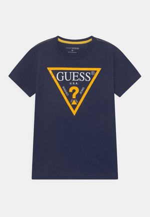 T-shirt bleu marine à manches courtes avec logo triangulaire Guess bordé de jaune et texte "GUESS U.S.A. Washed Jeans" centré sur la poitrine.