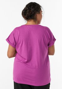 Lühikeste mängusärgi varrukatega, lahtine magenta särk; pehme kangas rullitud varrukatega ja ümar kaelus; sile tekstuur ilma dekoratiivsete detailideta.