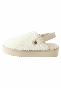 Chausson blanc duveteux avec une tige texturée, des accents en suède beige, une sangle arrière et une semelle épaisse et moulée. Doublure intérieure douce visible.
