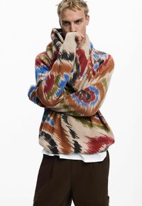 Maglione lavorato a maglia multicolore con un design accogliente e oversize, colletto alto, intricati motivi floreali e texture a coste.