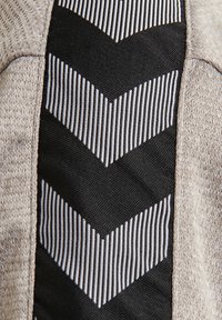 Nabij een stofdetail met een beige en grijze stof en een centraal zwart paneel dat een zigzagpatroon toont met afwisselende witte en zwarte strepen.