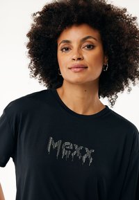 Schwarzes T-Shirt mit Rundhalsausschnitt, das mit einem mit Kristallen besetzten Design verziert ist, das "Merry" in einem tropfenden Schriftzug über die Brust spell.