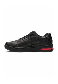 Black leather sneaker with a textured upper, perforated details, flat laces, and a red accent on the midsole. Sleek, rounded shape.