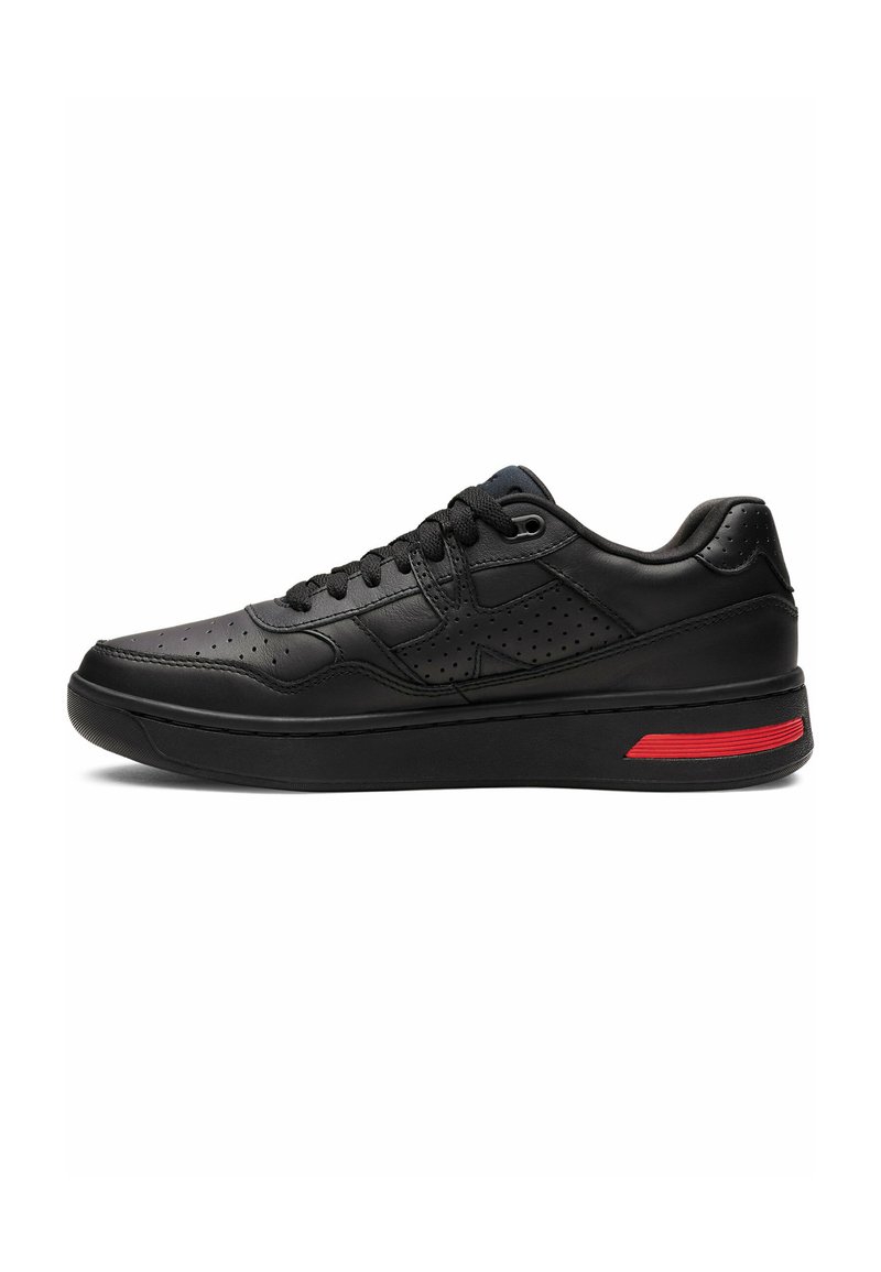 Black leather sneaker with a textured upper, perforated details, flat laces, and a red accent on the midsole. Sleek, rounded shape.