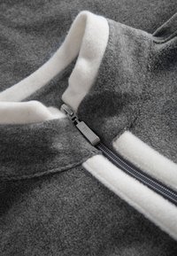 Gray fleece jacket with white collar trim and zipper detail. Soft texture with contrasting white stripes on the collar and zipper area.